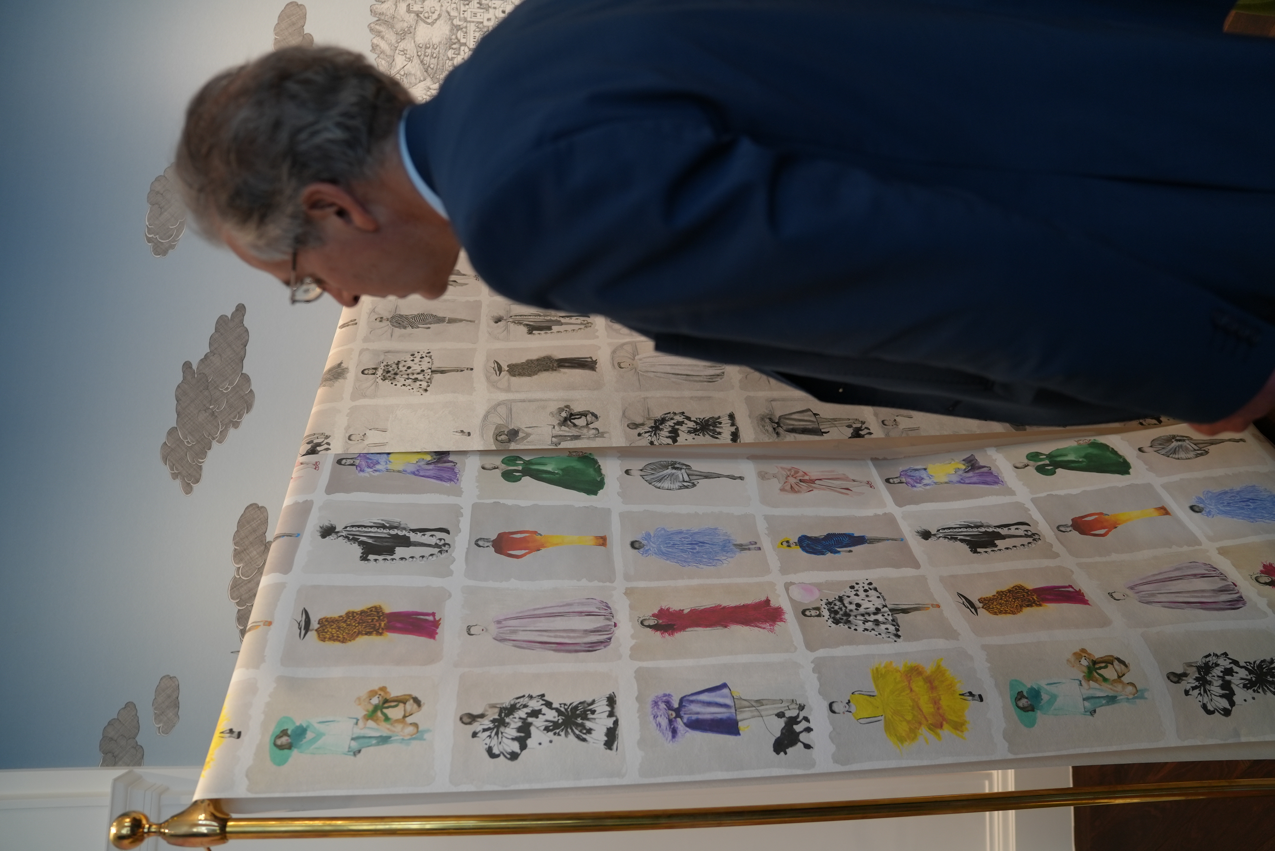 Cole & Son - a man looking at a sheet of fashion drawings hung on a rail