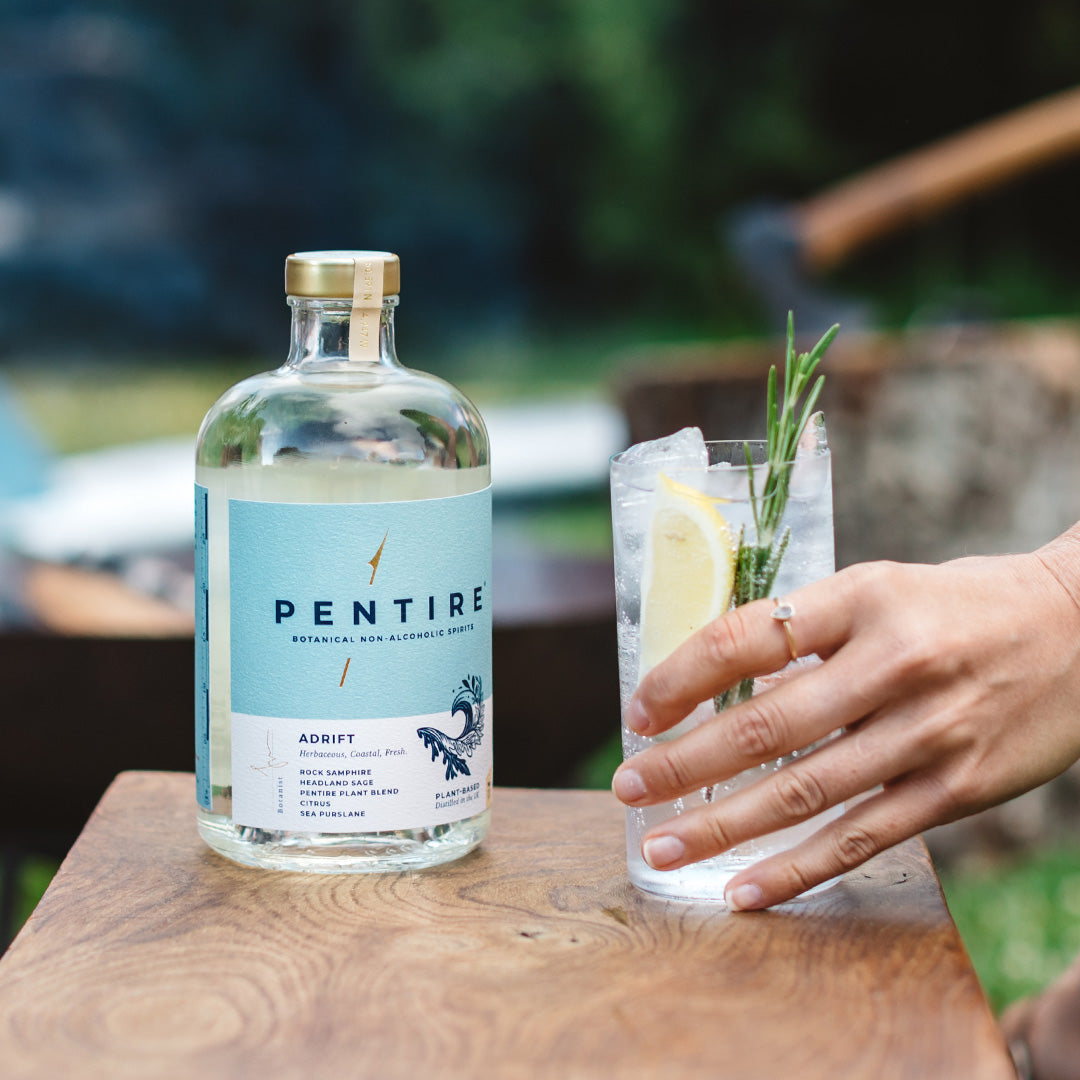 luxury non alcoholic spirits - a bottle of pentire adrift aside a glass with lemon and herbs