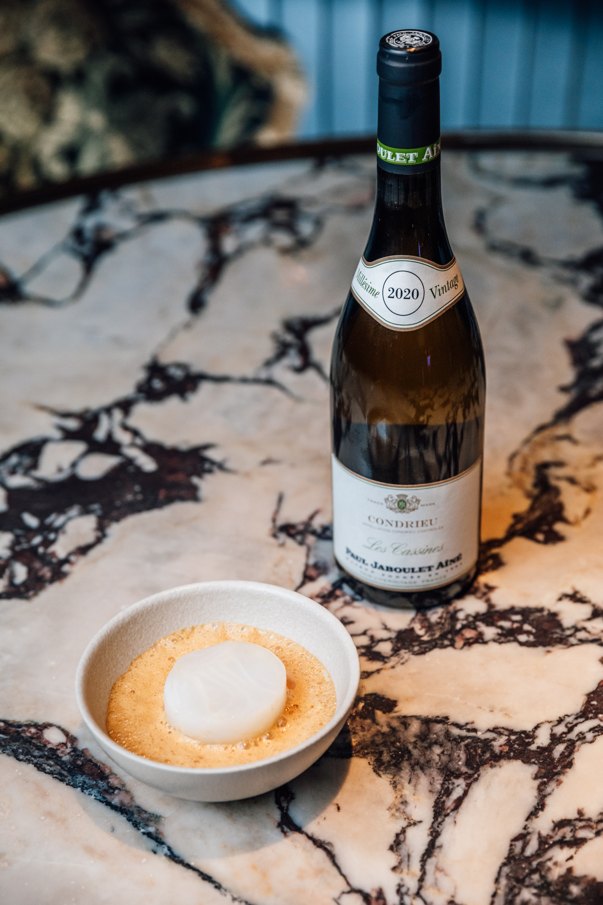 Royal Ascot Restaurants 2025 - a cod dish in white bowl alongside a bottle of wine