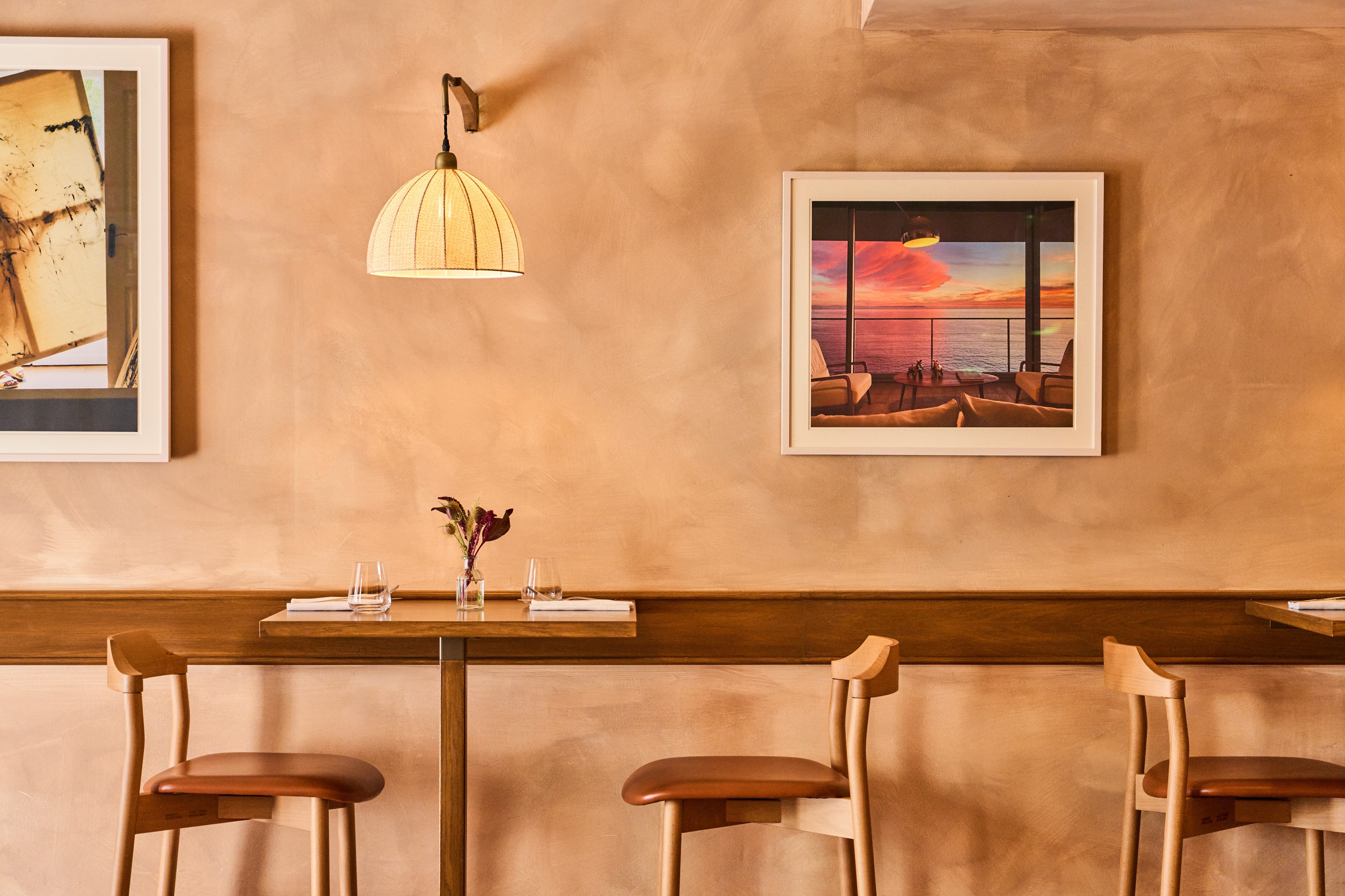 Art restaurants in London - The interior of Lolo on Bermondsey Street featuring Peter Meades' Brillo Rojo on a terracotta wall. Two wooden tables with matching chairs are laid for a meal.