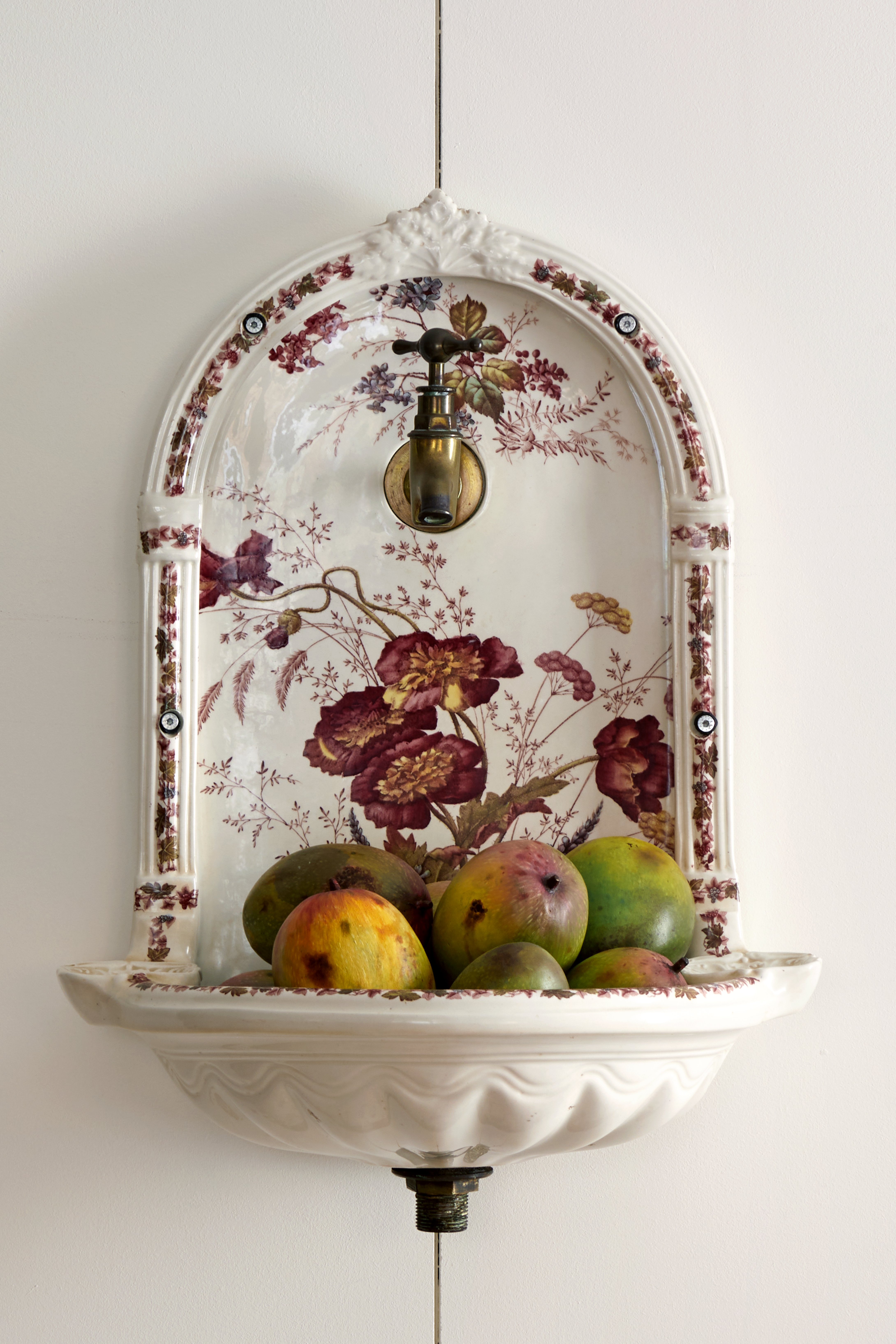 Art restaurants in London - A decorative vintage ceramic wall fountain at Mount St. Restaurant with intricate floral patterns. Fruit fills the basin.